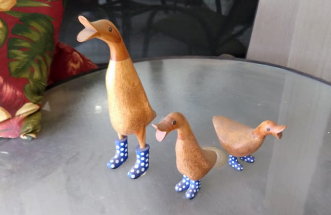 Three sculptures of ducks wearing shoes