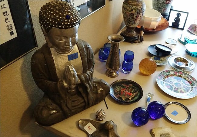 Large Buddha on table with plates and vases